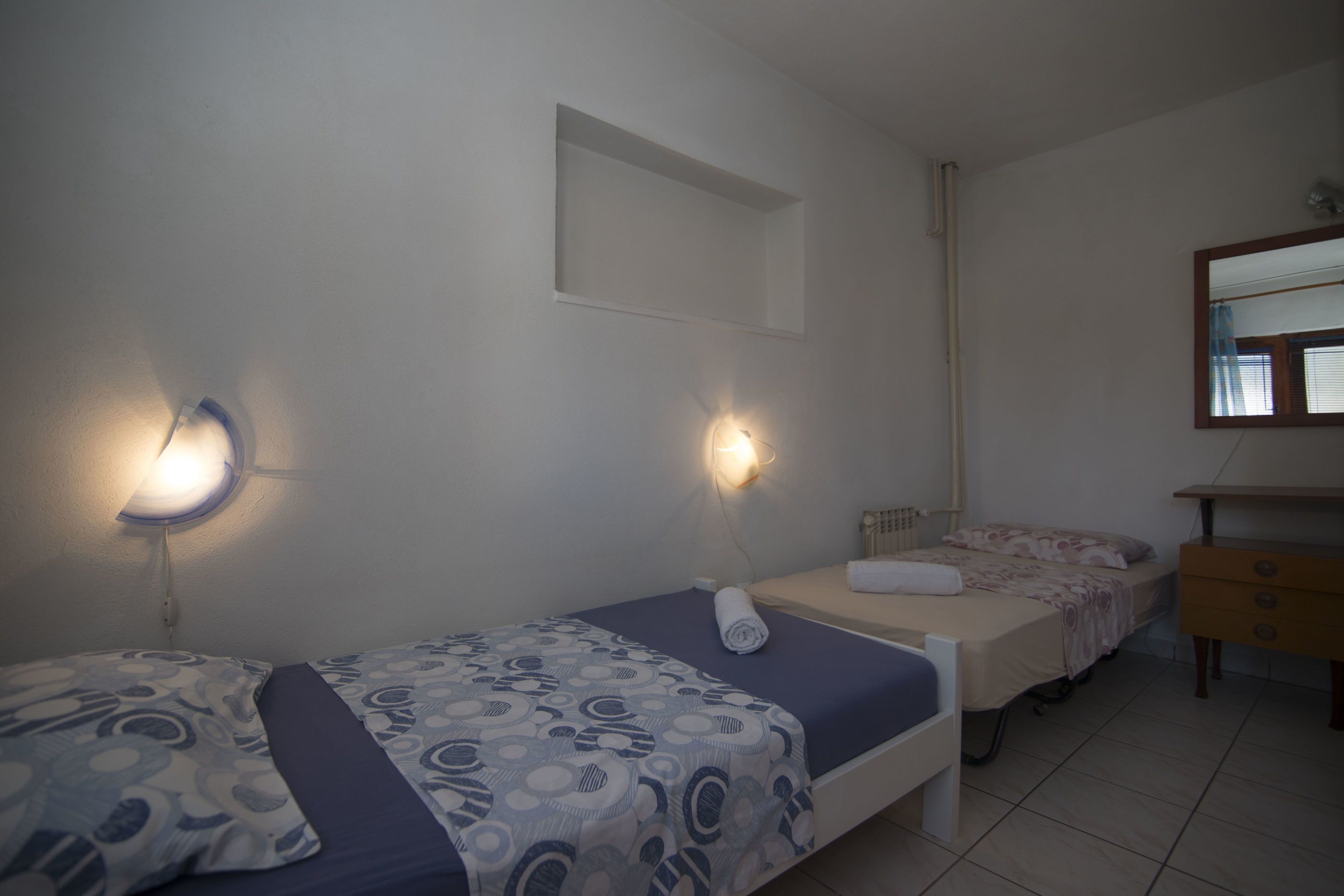 Un dormitorio con dos camas, un aparador y un espejo.