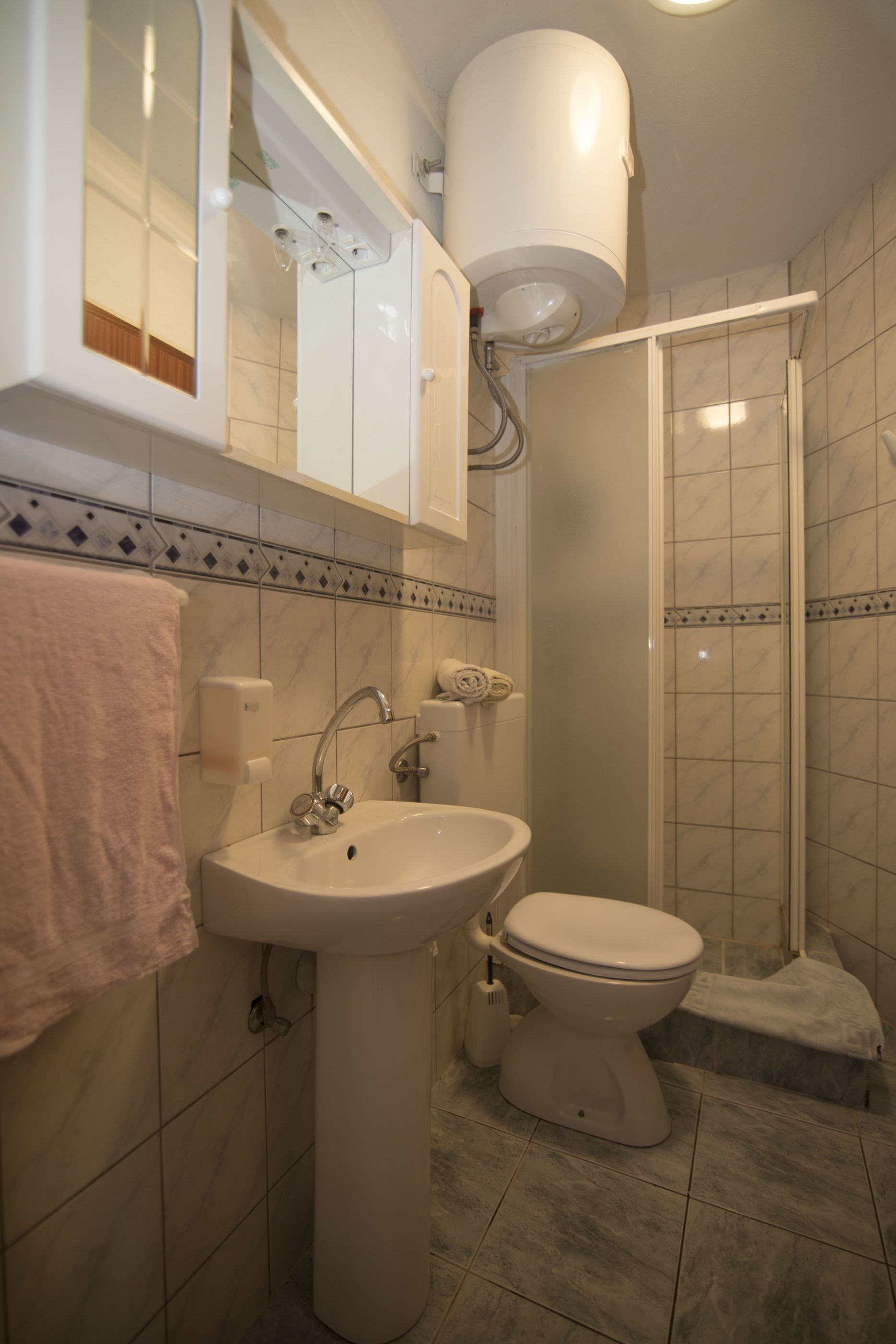 A bathroom with a sink, toilet, and a shower enclosure.