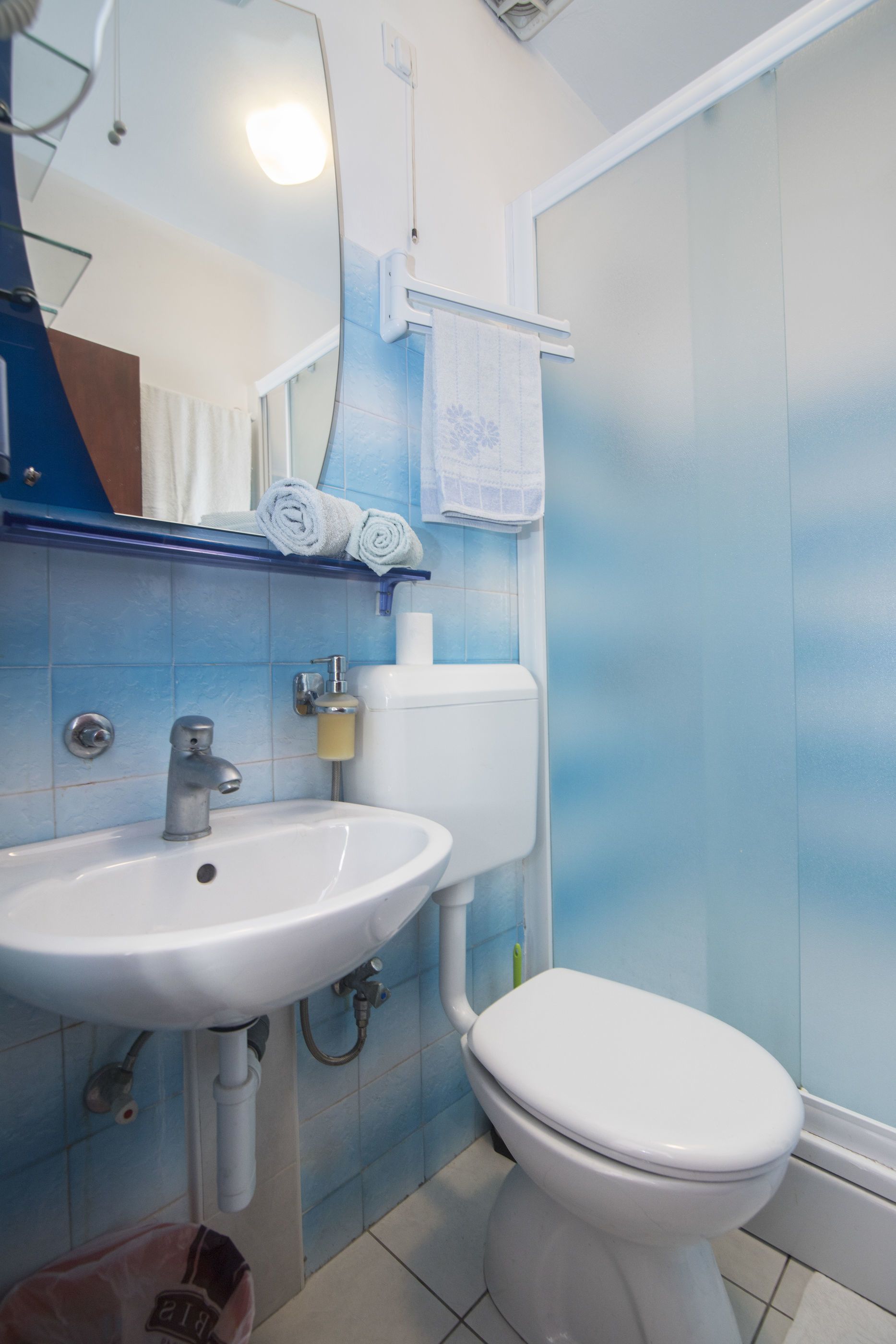 Ein Badezimmer mit einem weißen Waschbecken, einer Toilette und blautonierten Fliesen.