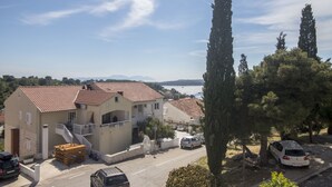 A coastal building with a tiled roof, a staircase, and a view of the sea. - Apartments and Rooms Nikol (Hvar)