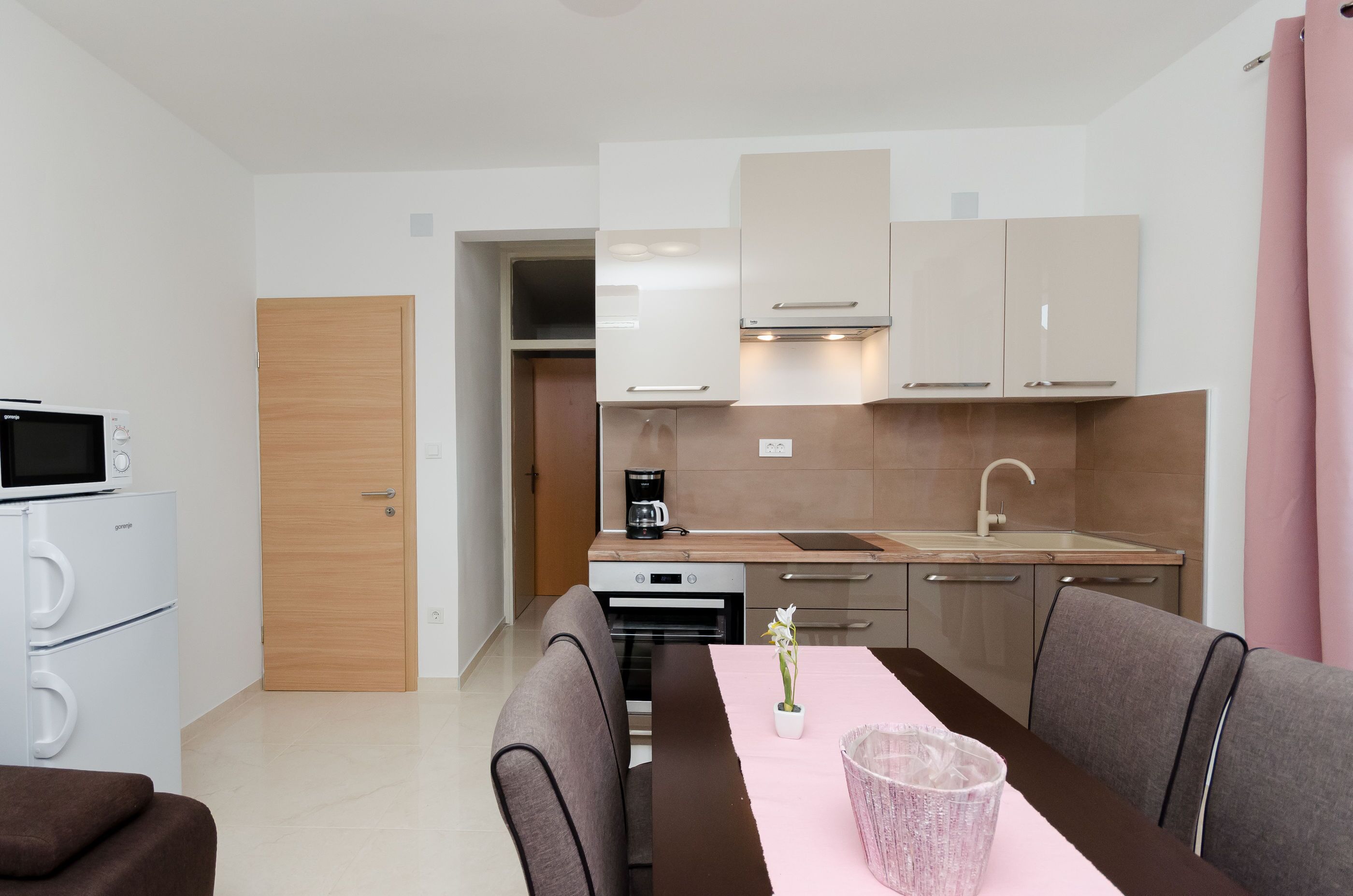 Une cuisine compacte dotée d’appareils électroménagers modernes, un coin repas avec une table et des chaises, et un petit réfrigérateur.