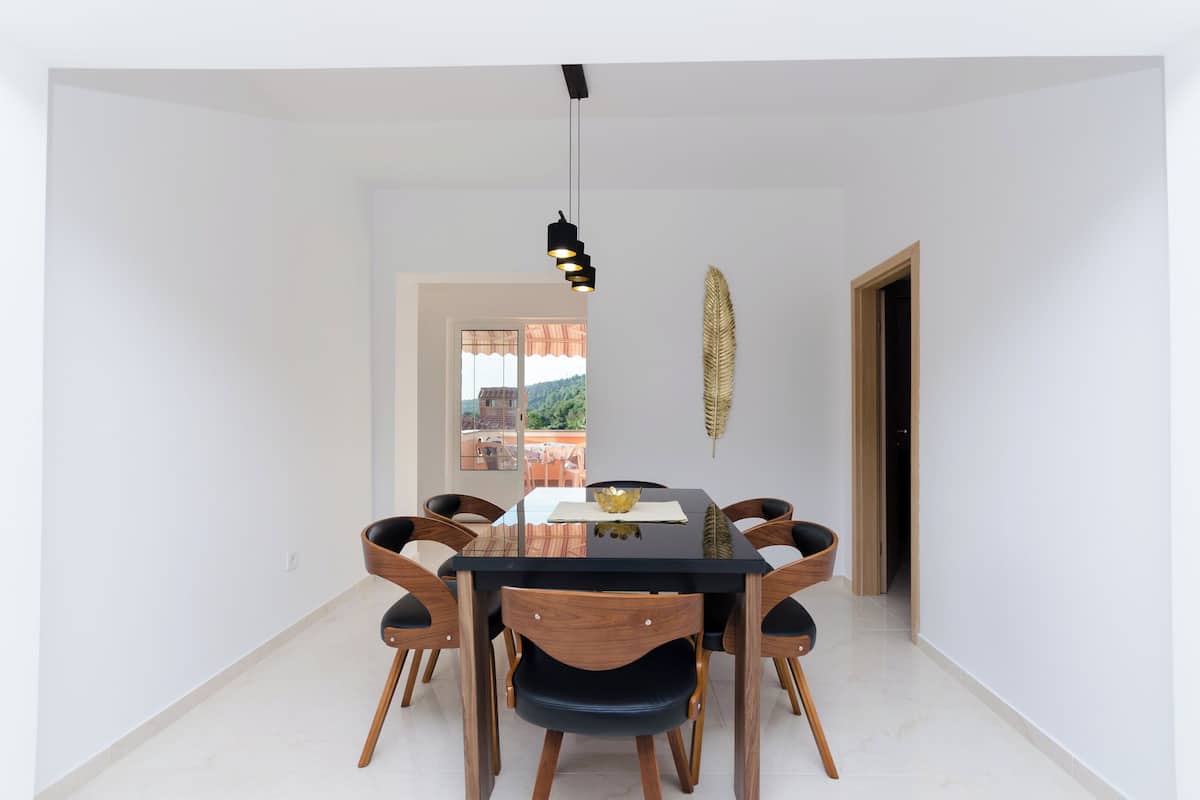 Ein Essbereich mit einem schwarzen Tisch, sechs Holzstühlen und einer Pendelleuchte.