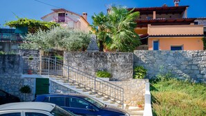 A residential area with stone walls, a staircase, and parked cars. - Apartments Ester (Funtana)