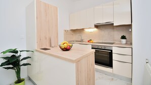 A modern kitchen with white cabinets, a wooden countertop, and a built-in oven. - Apartments Ester (Funtana)