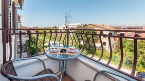 A balcony with a table set for two, overlooking a residential area with houses and greenery. - Apartments Luciana (Rovinj)