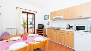 A compact kitchen with wooden cabinets, a microwave, and a sink. - Apartments Luciana (Rovinj)
