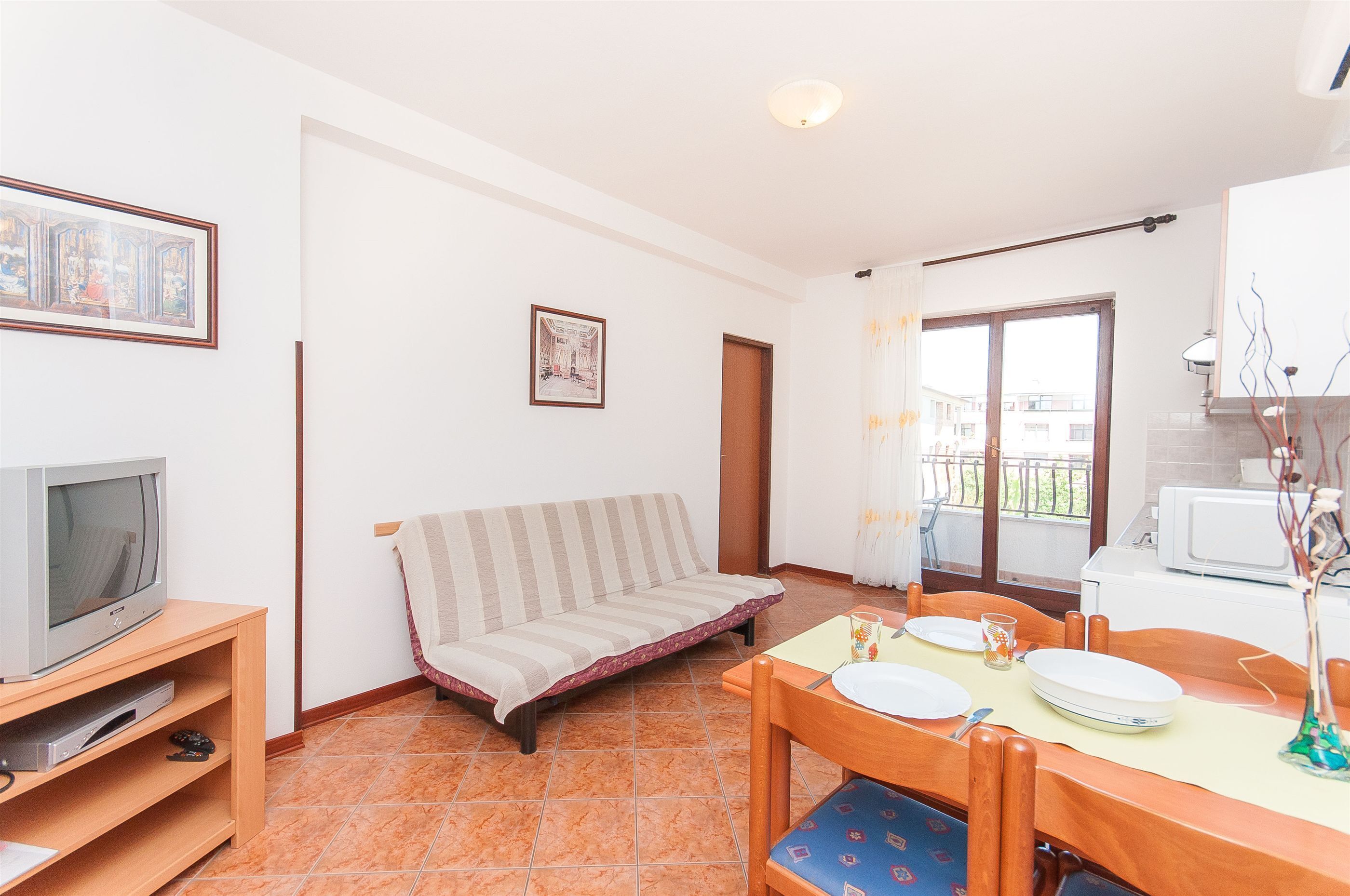 Un salon comprenant un canapé, un téléviseur, une table à manger avec des chaises et un balcon avec vue.