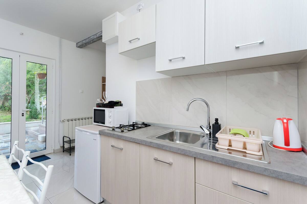 A modern kitchen with a built-in microwave, gas stove, and sink. There is a small refrigerator and a coffee maker on the counter.
