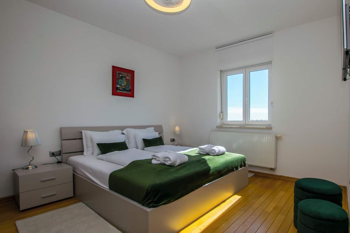 A modern bedroom with a bed, bedside tables, a window, and a radiator.