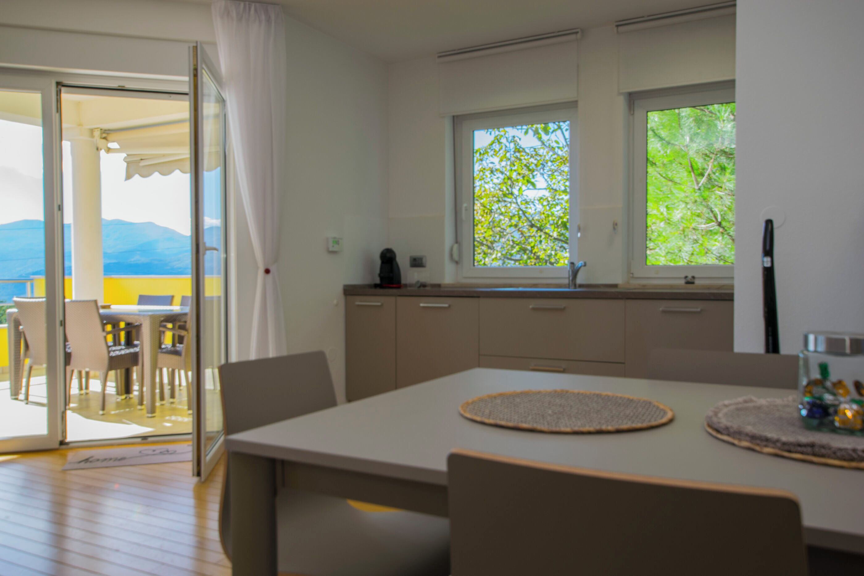 A modern kitchen with a large window, a dining area with a table and chairs, and a view of the outdoors.