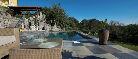 A swimming pool with a glass top, surrounded by stone steps and a wicker sofa.