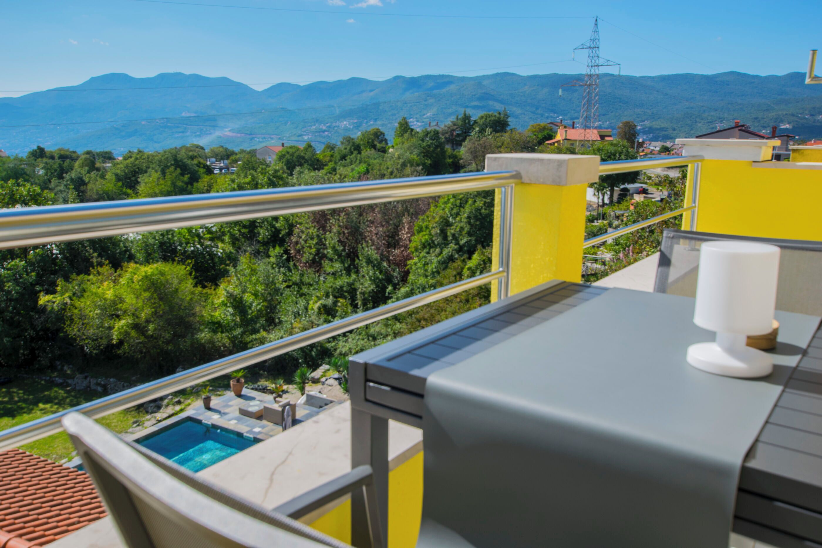 Un balcon avec une piscine, des murs jaunes et une vue sur les montagnes.