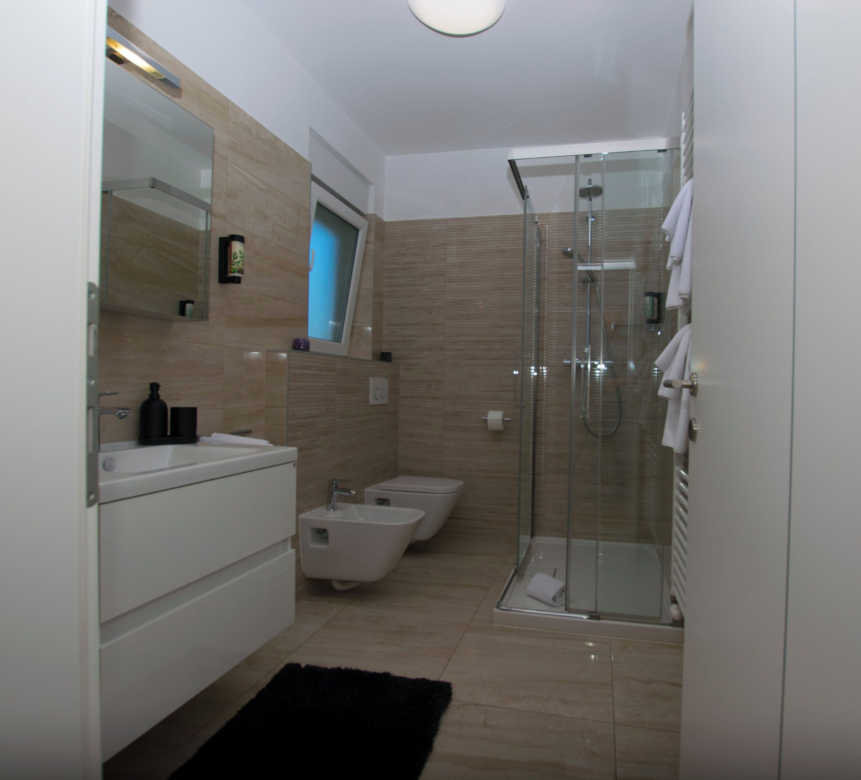A modern bathroom with a glass shower enclosure, a bidet, and a toilet.