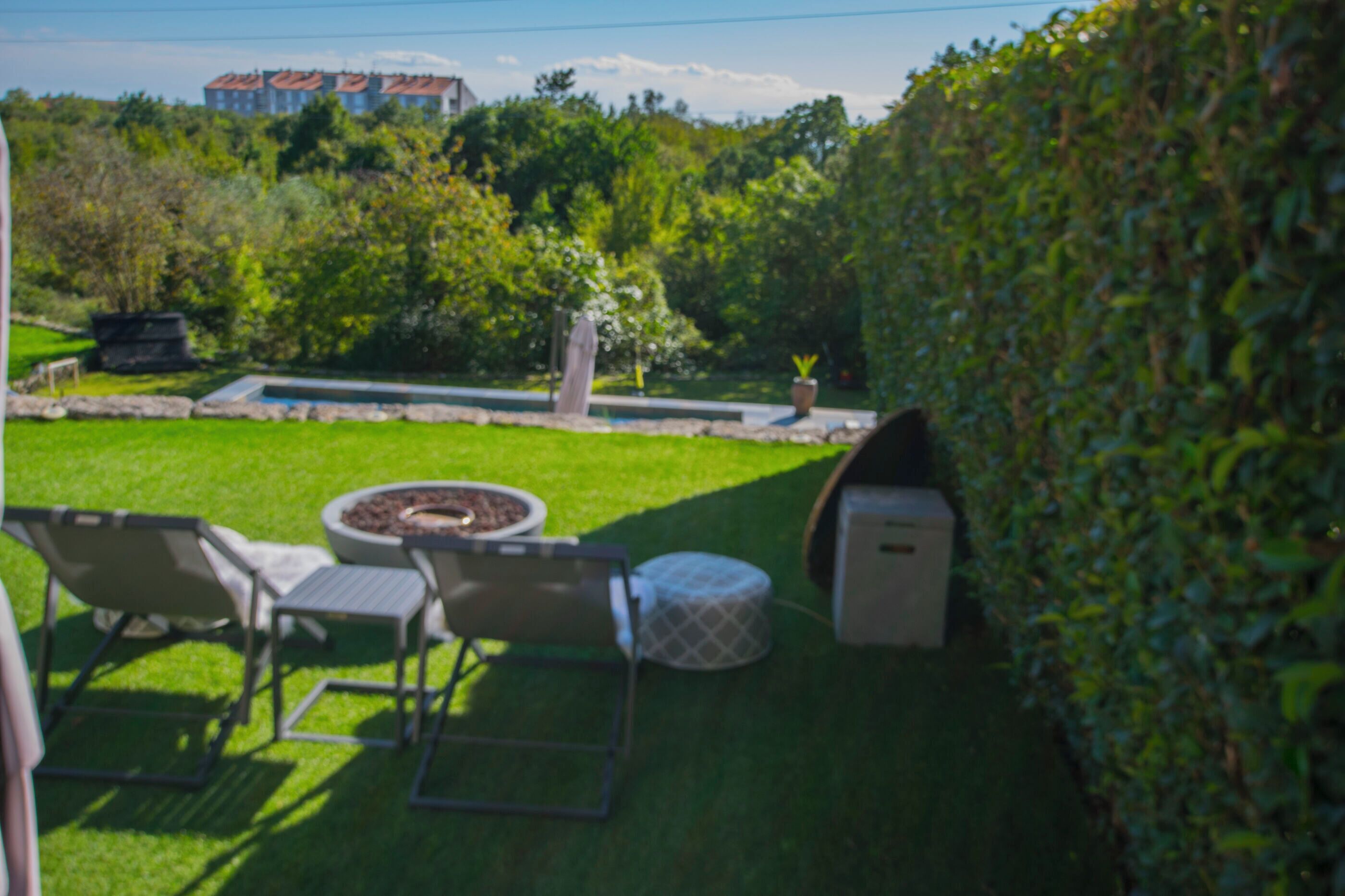 Un jardin avec un espace aménagé pour s’asseoir, un foyer et une plante en pot.