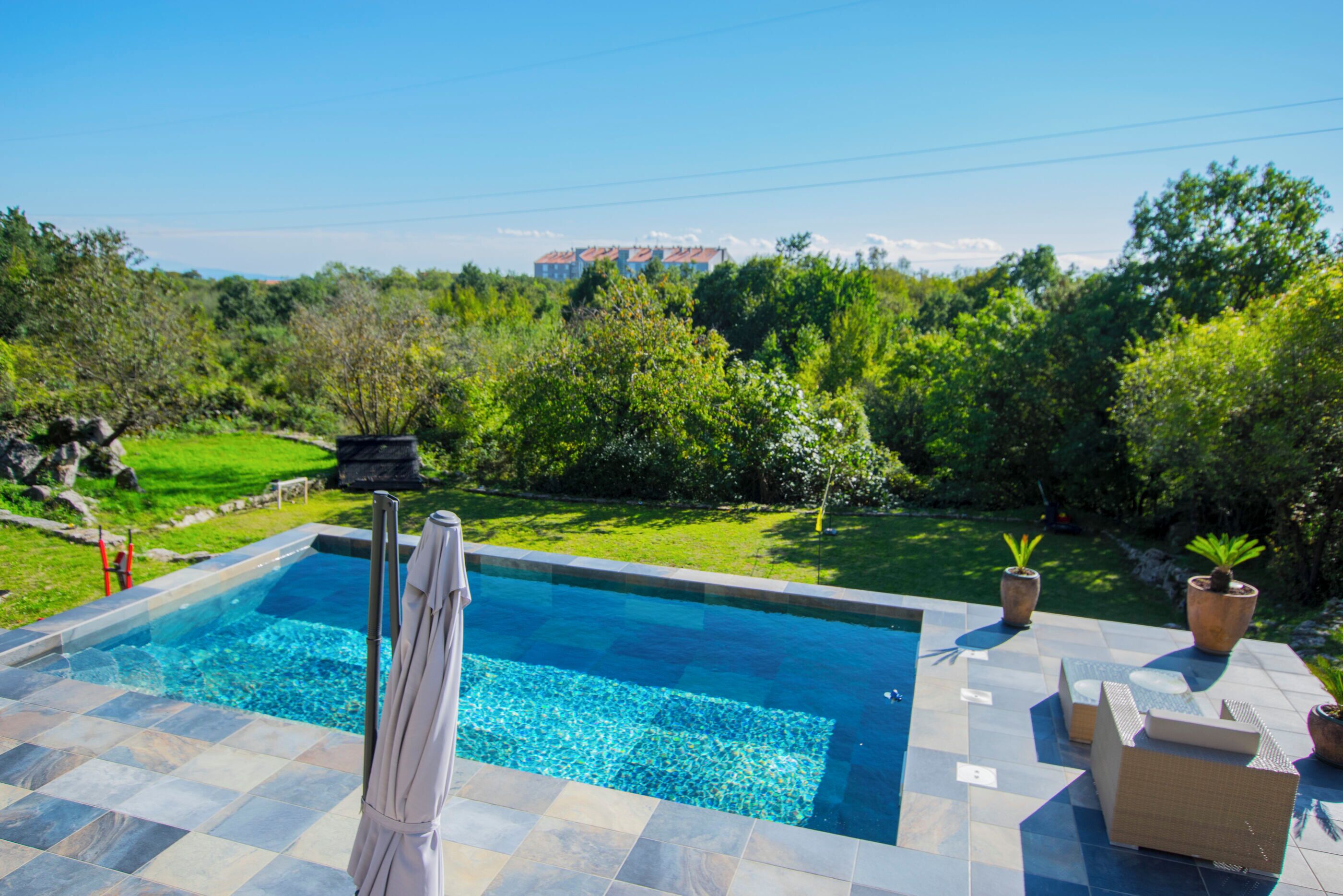 Een buitenzwembad, parasols bij het zwembad en ligstoelen