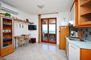 A compact kitchen with a dining area, a built-in oven, and a view through the glass door. - Apartment Andreas (Rasa)