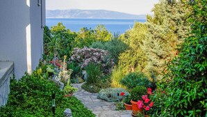 A garden pathway leading to a scenic view of the sea. - Apartment Andreas (Ravni)