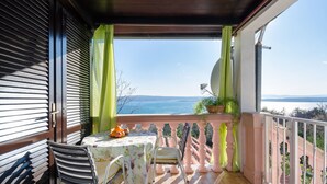 Ein Balkon mit Tisch und Stühlen, Blick aufs Meer und einem Geländer.