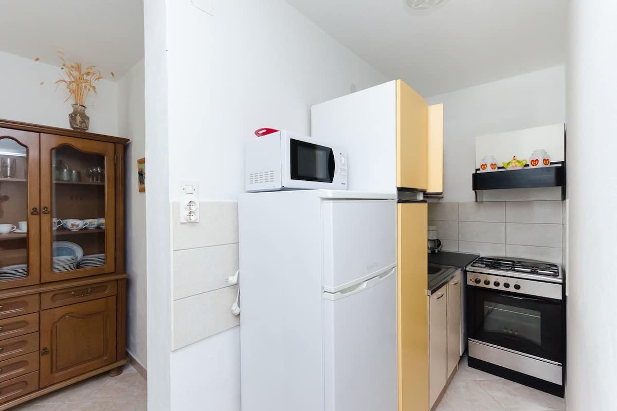 Une cuisine de taille réduite, avec un réfrigérateur blanc, un four à micro-ondes, une cuisinière et un meuble en bois.