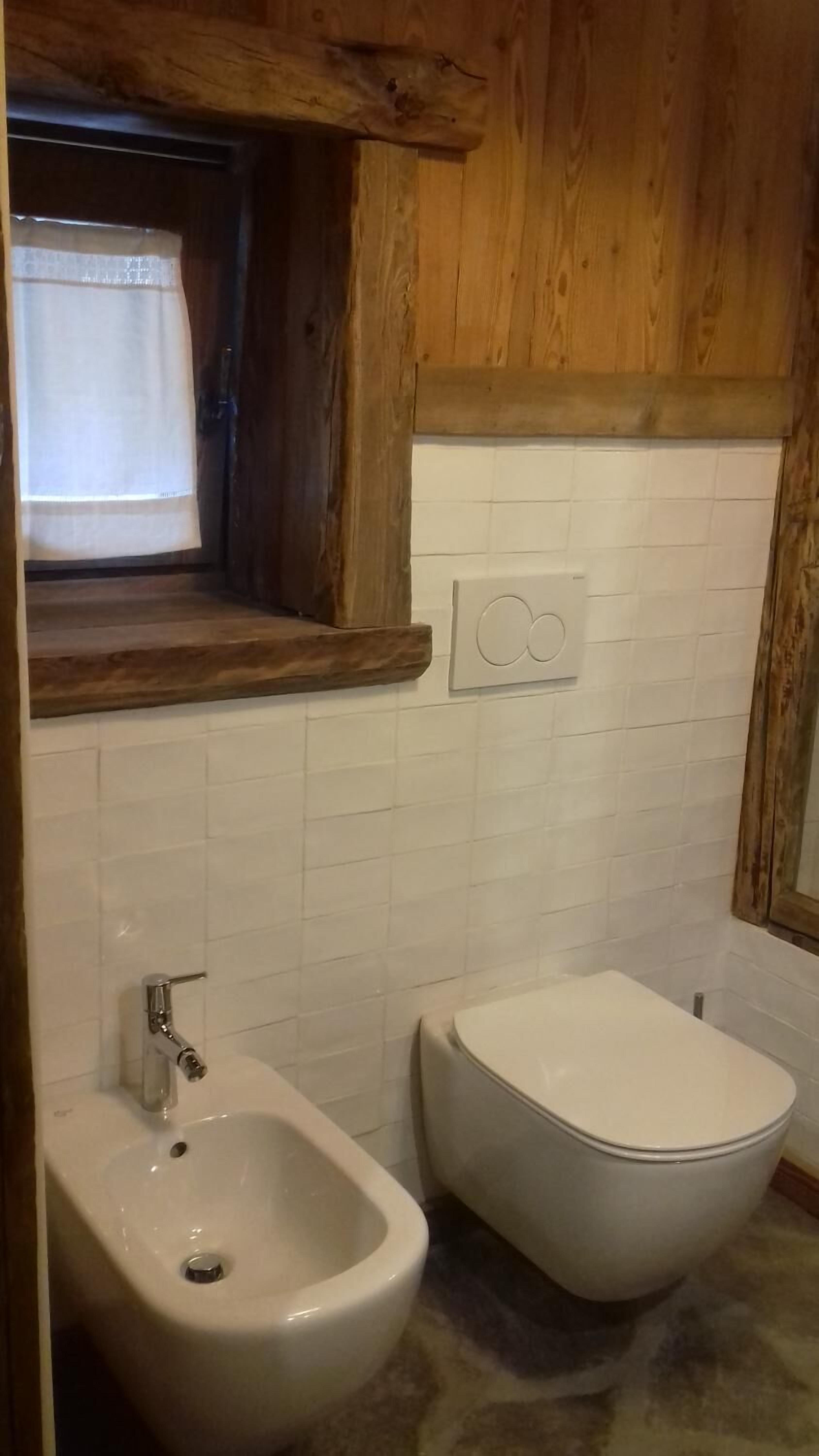A bathroom with a wooden vanity, a bidet, and a sink.