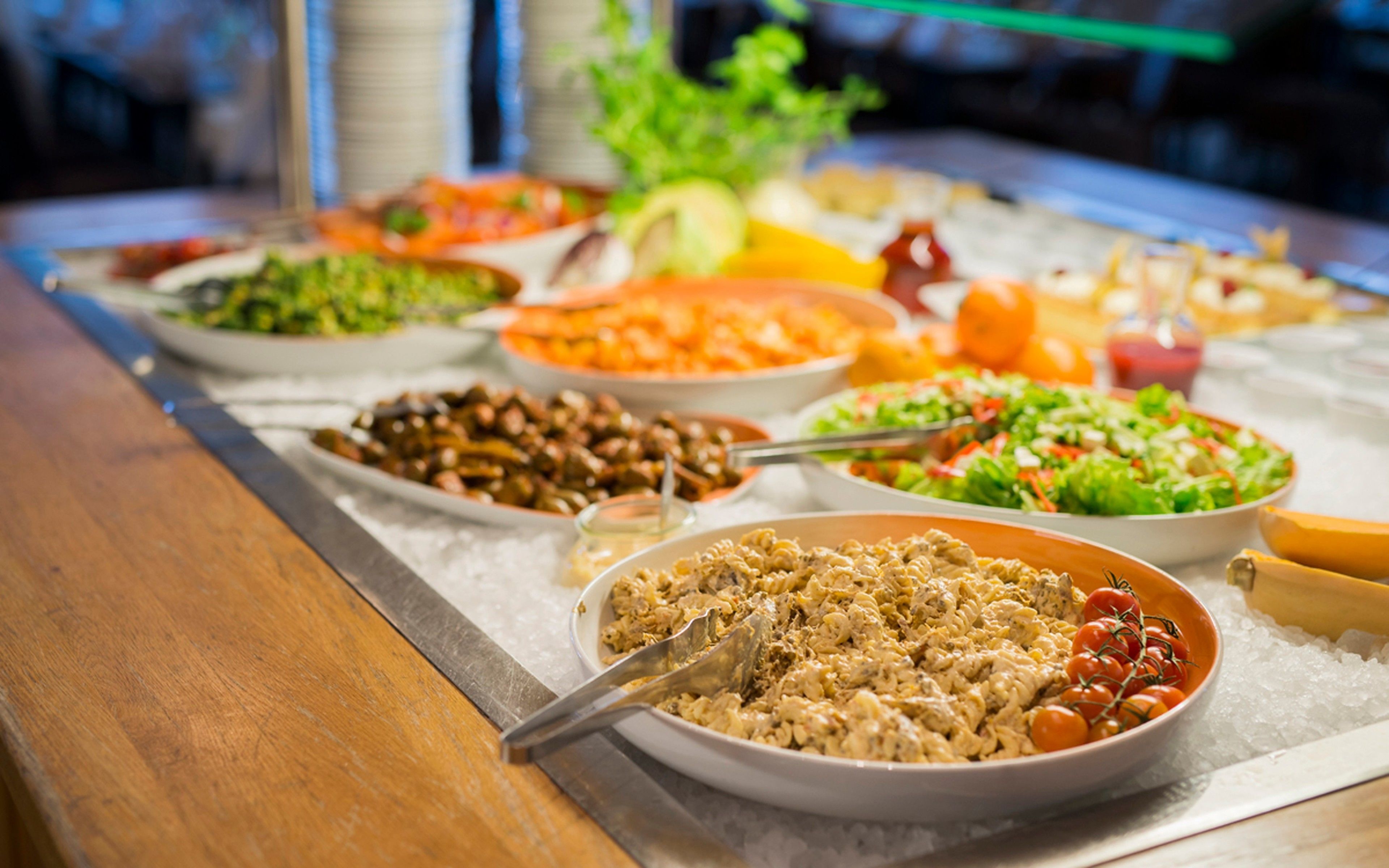 A buffet table with various dishes including pasta, salads, and vegetables.