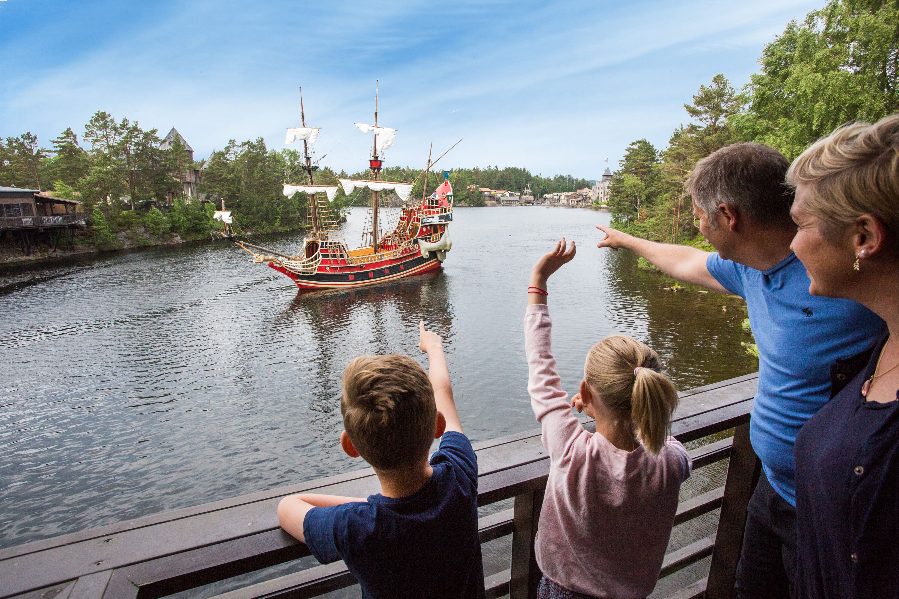 A family observing a large, colorful ship on a river.