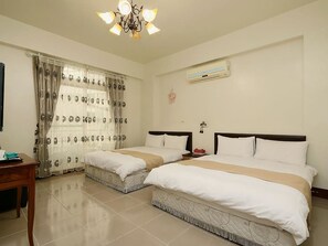 A hotel room with two beds, a desk, a chandelier, an air conditioner, and a window with curtains. - Leisure Homestay (Hualien City)