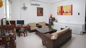 A living room with a sofa, armchairs, a coffee table, and a TV. There is a kitchen area with cabinets and a refrigerator. - Leisure Homestay (Hualien City)