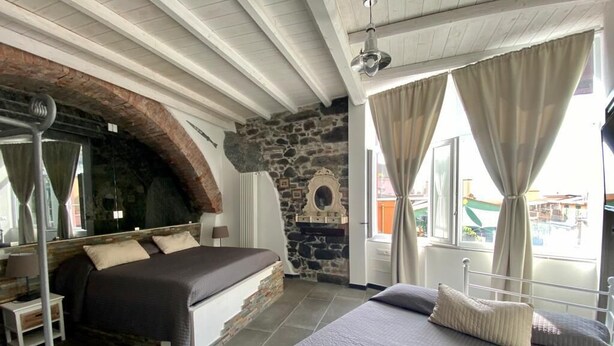 A bedroom with a stone wall, a bed, a window with curtains, and a view of the outside. - 5 Terre Pelagos 2 (Riomaggiore)