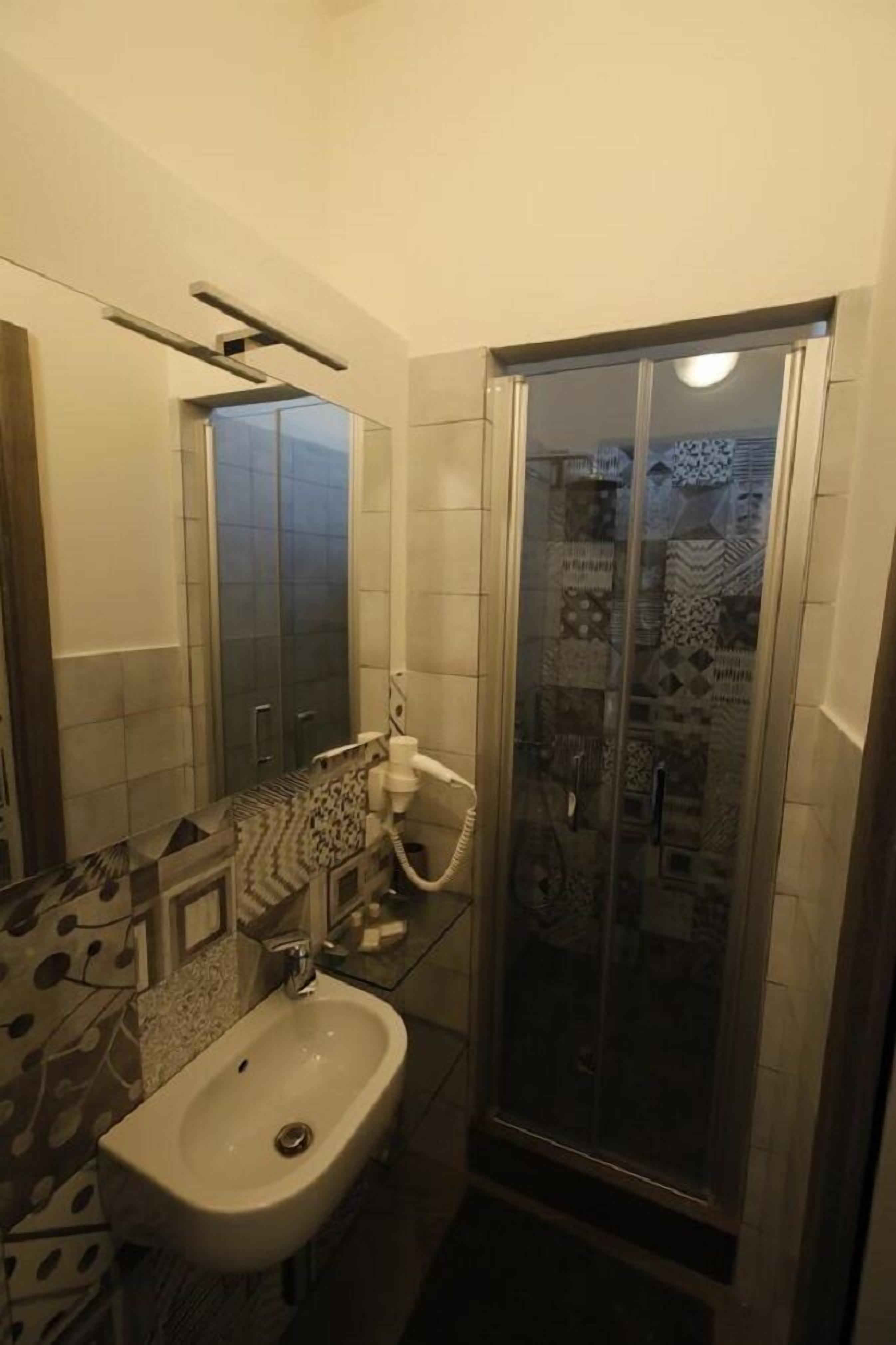 A bathroom with a bidet, a glass shower enclosure, and patterned tiles.
