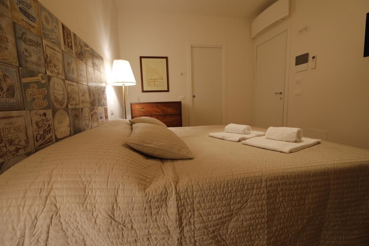 A neatly made bed with a quilted cover, a wooden headboard, and two neatly folded towels on the bed.