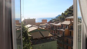 A coastal view from a window overlooking a town with buildings and a clear sky. - 5 Terre Pelagos 2 (Riomaggiore)