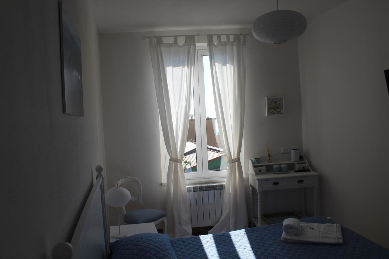 A bedroom with a bed, a desk, a chair, and a window with curtains.