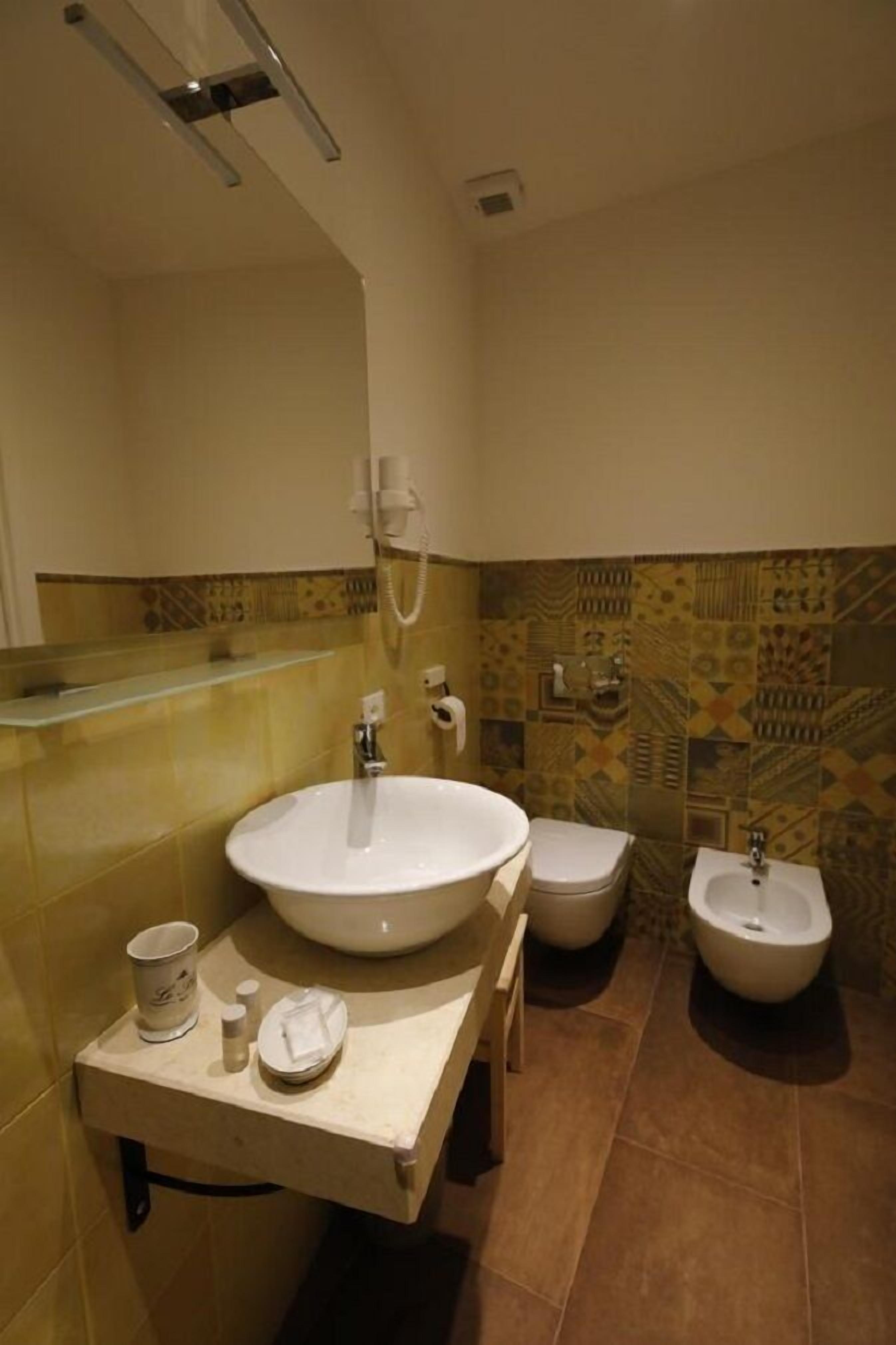 A bathroom with a large sink, two toilets, and a bidet.