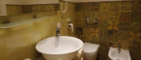 A bathroom with a large sink, two toilets, and a bidet.