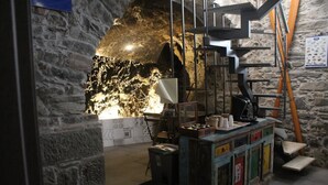 A rustic interior with a stone wall, a wooden ladder, a metal staircase, and a counter with various items. - 5 Terre Pelagos 2 (Riomaggiore)