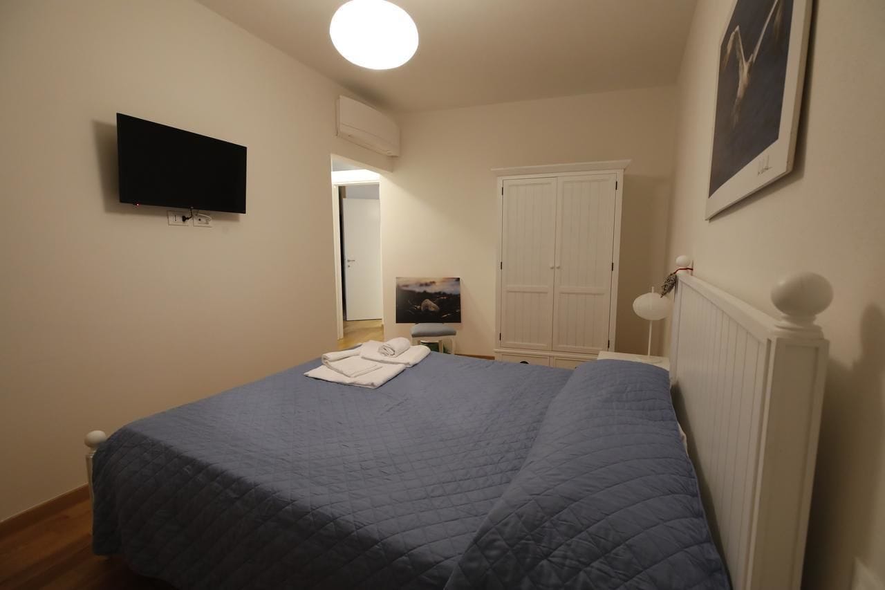A bedroom with a bed, a flat-screen TV, a wardrobe, and a framed picture on the wall.