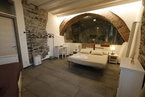 A bedroom with a stone wall, a large arched window, a bed, a chair, a nightstand, and a wardrobe. - 5 Terre Pelagos 2 (Riomaggiore)