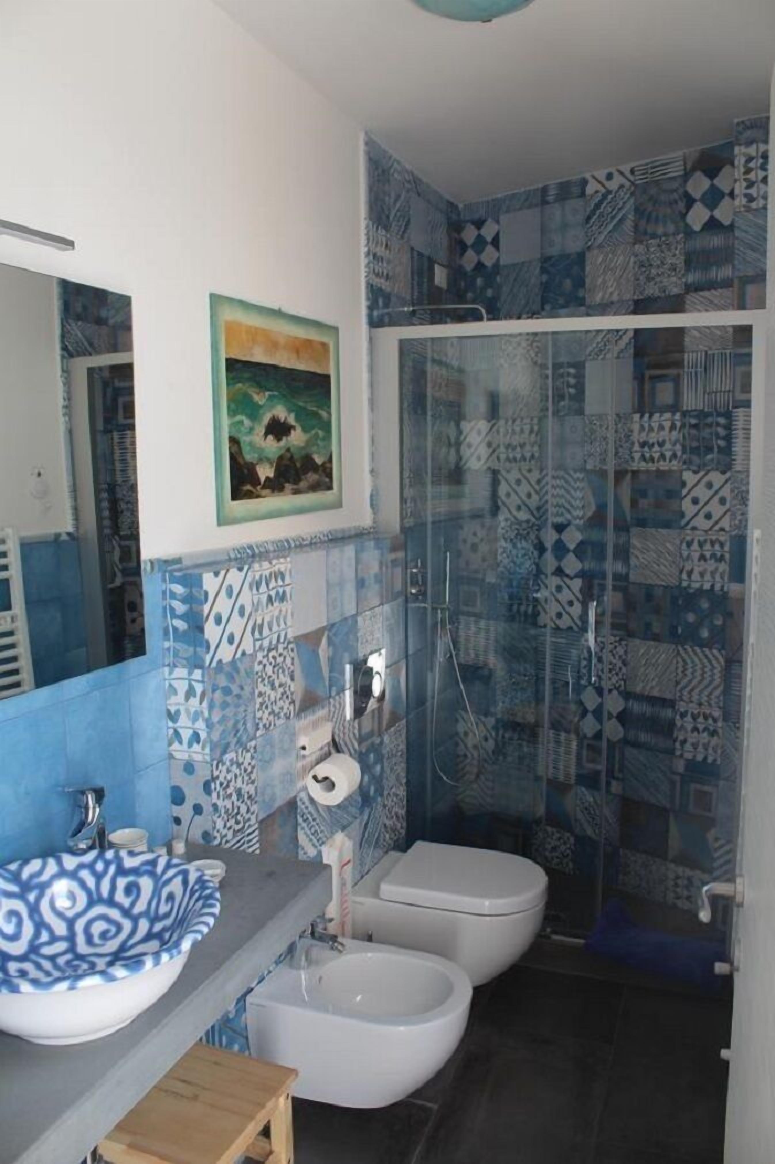 Ein Badezimmer mit Dusche, zwei Toiletten, Waschbecken und Spiegel.