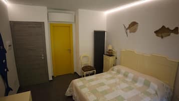 Une chambre à coucher avec un lit, une chaise, un bureau, un radiateur et une porte.