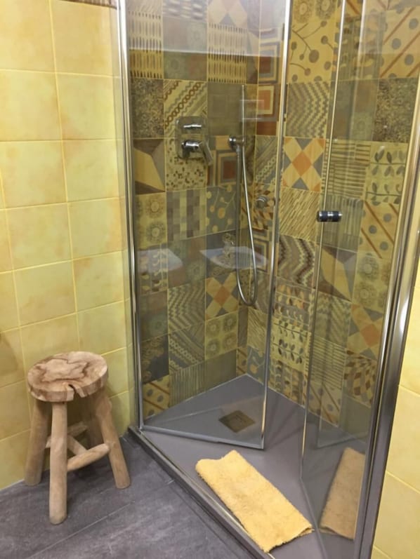 A shower area with patterned tiles, a glass enclosure, and a wooden stool. - 5 Terre Pelagos 1 (Manarola)