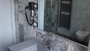 Un baño moderno con un lavamanos grande y rectangular, una cabina de ducha con paredes de vidrio y un perchero para toallas.