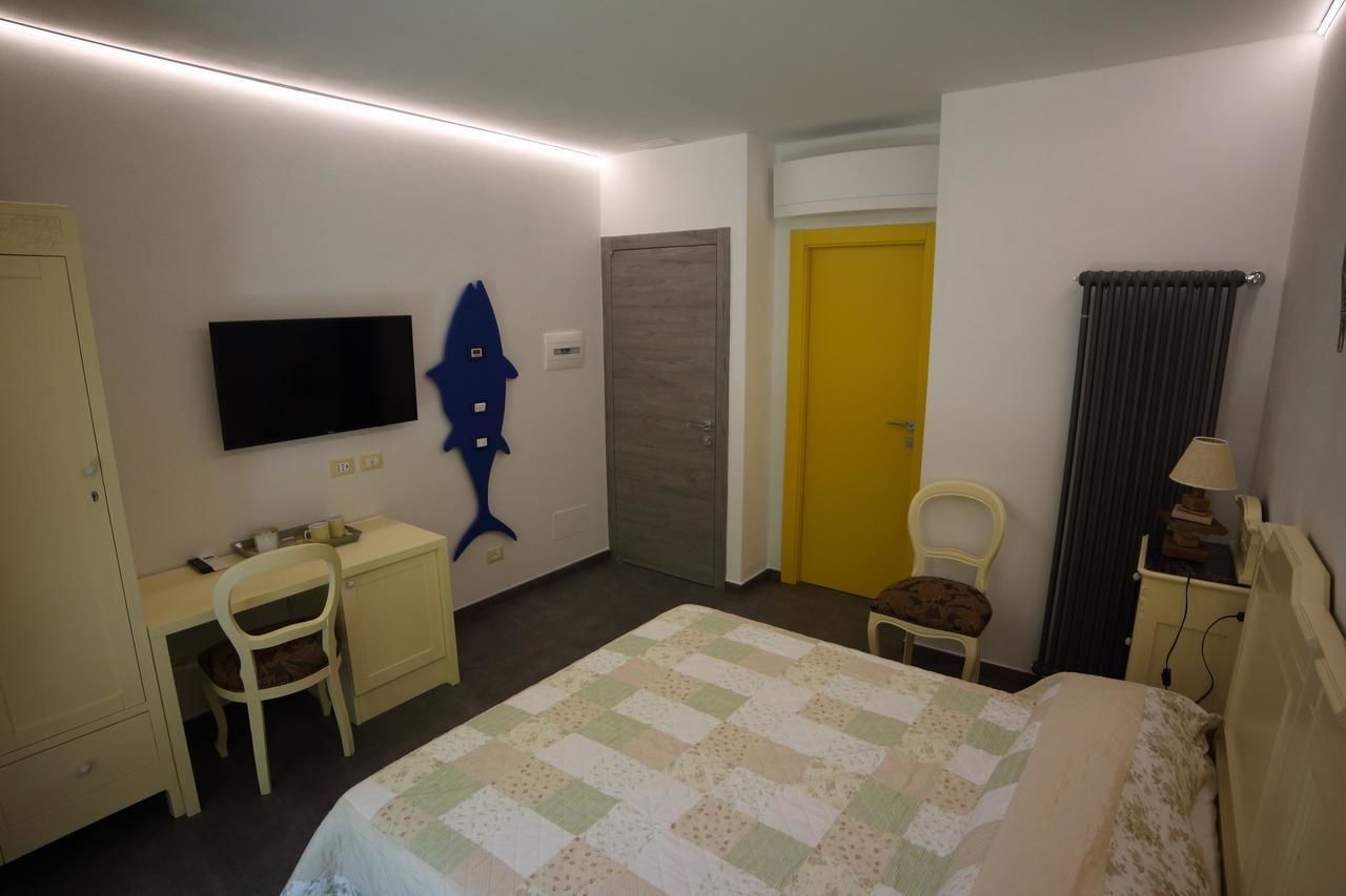 A hotel room with a bed, a desk, a chair, a television, a door, and a radiator.