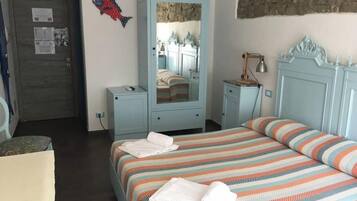 A bedroom with a bed, a wardrobe, a mirror, a lamp, and a fish decoration on the wall.