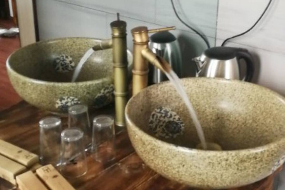 A bathroom with two large ceramic sinks, a wooden table, and a mirror.