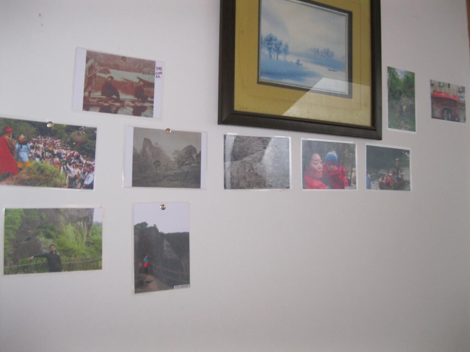 A wall with various photographs and a framed picture.