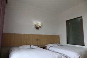 A hotel room with two single beds, a wooden headboard, a wall-mounted light fixture, and a large window. - Wuyishan City Chun Hui Traders Hotel (Nanping)