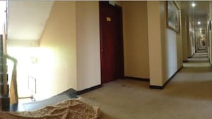 A hotel hallway with carpeted stairs leading to a landing, a red door, and a long corridor with doors on both sides. - Wuyishan City Chun Hui Traders Hotel (Nanping)