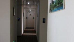A hotel hallway with patterned carpet, a painting on the wall, and a door at the end. - Wuyishan City Chun Hui Traders Hotel (Nanping)