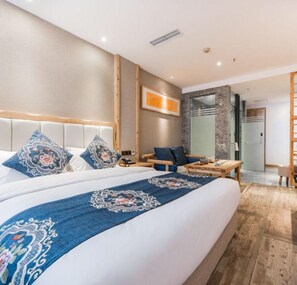 A modern hotel room with a large bed, a desk, and a shower area.